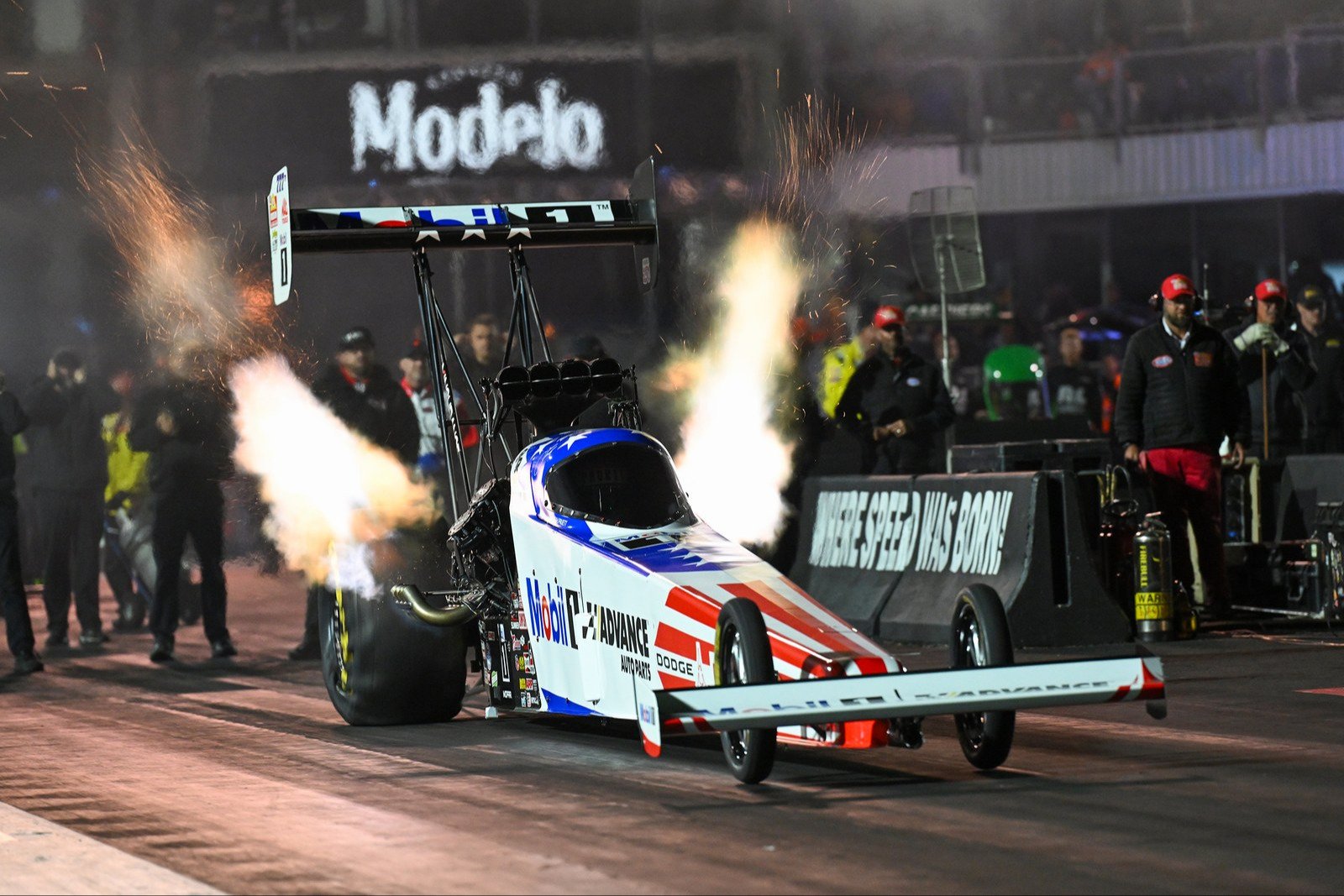 Leah Pruett's Mobil 1 Dodge Top Fuel dragster launching at night