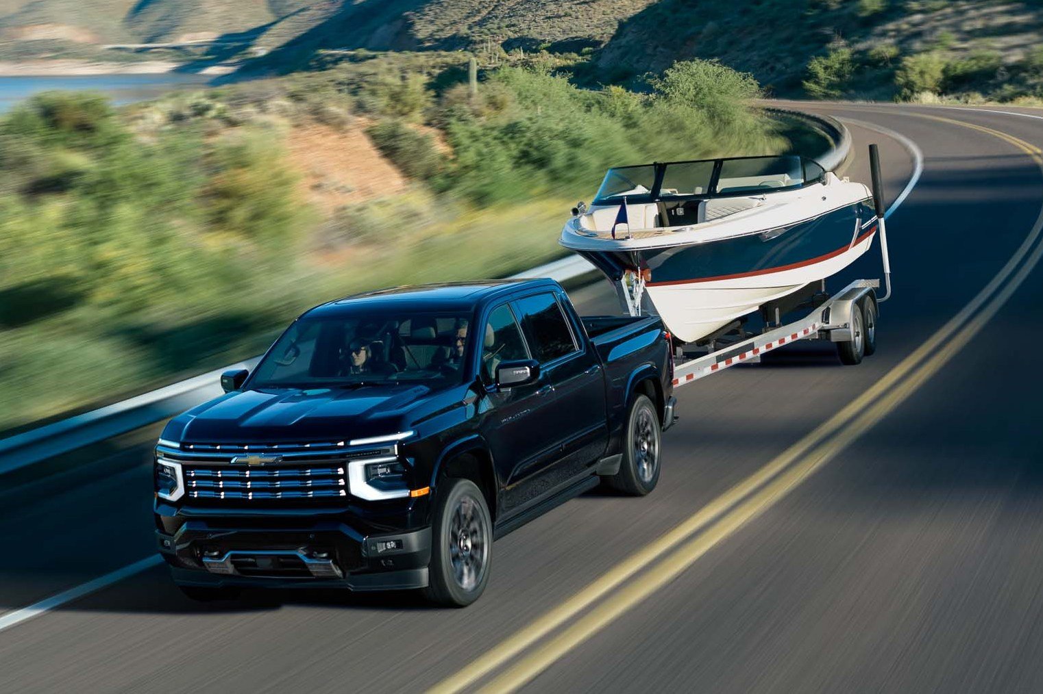 Black 2027 Chevrolet Silverado High Country towing a boat
