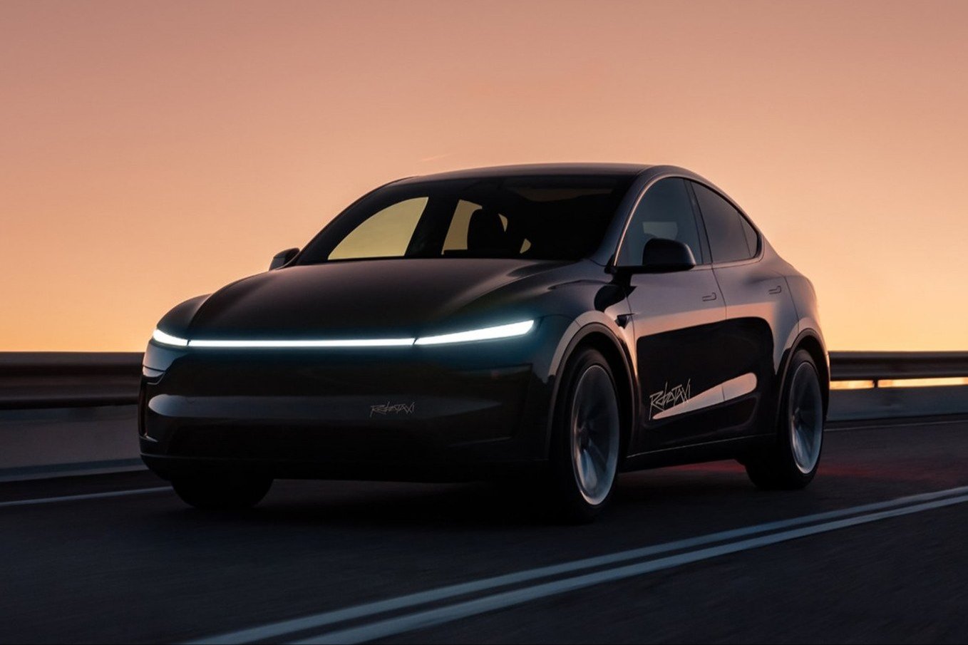Black Tesla Model Y Robotaxi on a highway at sunset
