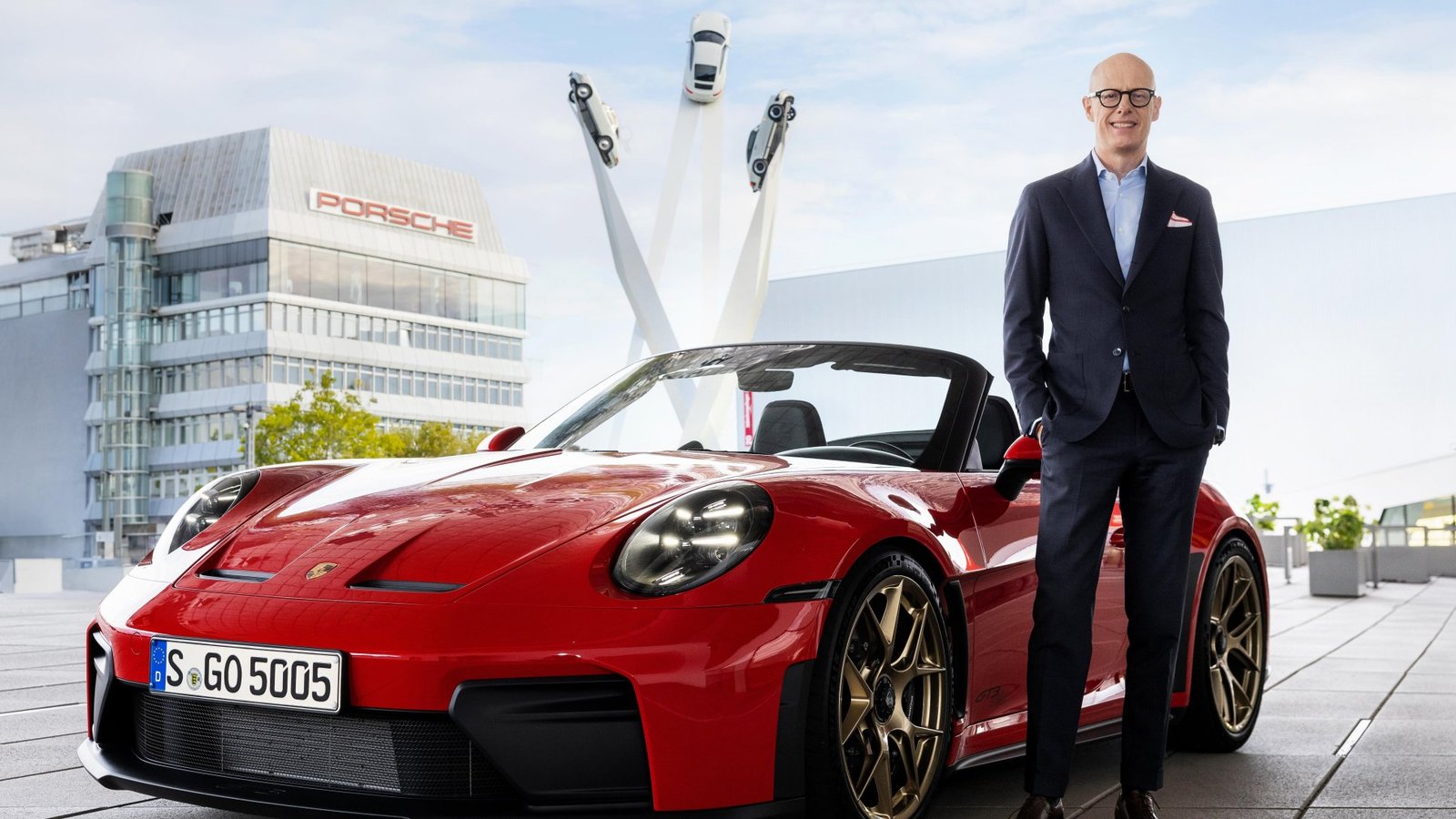 Porsche CEO Michael Leiters standing beside a red 911 convertible