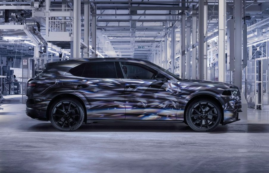 Camouflaged Bentley Torcal prototype in profile inside a factory