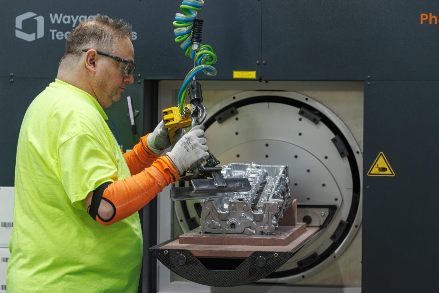 Worker loading an aluminum cylinder head into a CT scanner