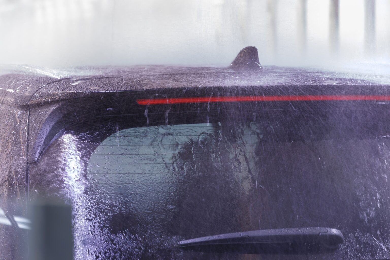 Water spraying over an SUV's rear glass in a leak-test booth